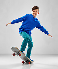 Image showing smiling boy in blue hoodie with skateboard