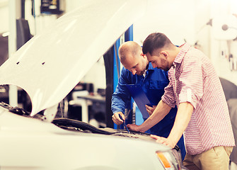 Image showing auto mechanic with clipboard and man at car shop