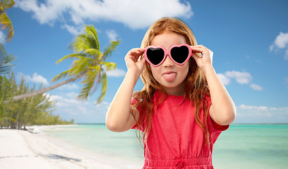 Image showing redhead girl in heart shaped sunglasses on beach