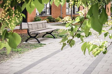 Image showing Bench and brick building seen through green leaves