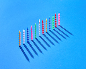 Image showing Vertical standing candles for cake with shadows, one is burning.