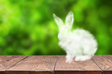 Image showing Cloud Easter Bunny on a wooden table against blurred green background.