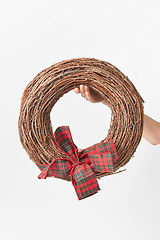 Image showing Round wreath from dry twigs with bow in a woman hand.