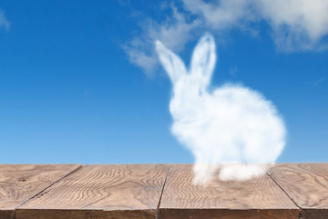 Image showing Cloud Easter rabbit on a wooden table against blue sky background.