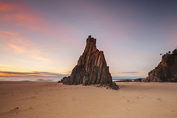 Image showing Pyramid sea stack on beach with beautiful sunrise sky with red c