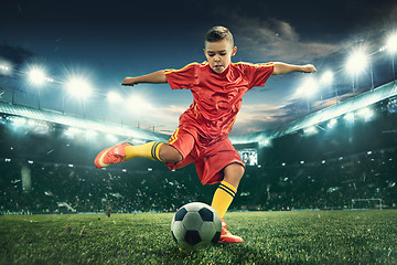 Image showing Young boy with soccer ball doing flying kick at stadium