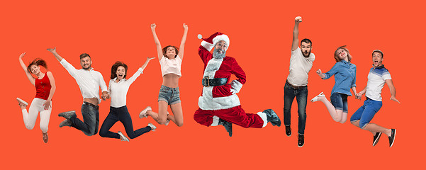 Image showing Freedom in moving. young man and women jumping against red background