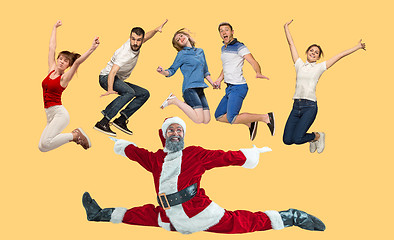 Image showing Freedom in moving. young man and women jumping against yellow background