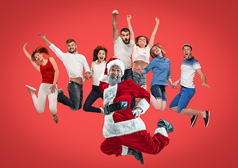 Image showing Freedom in moving. young man and women jumping against red background