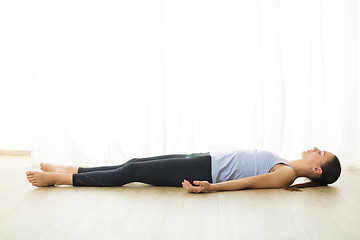 Image showing Portrait of gorgeous active sporty young woman practicing yoga in studio. Beautiful girl relaxing in Savasana, corpse pose. Healthy active lifestyle, working out indoors in gym