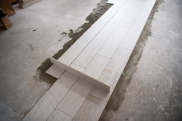 Image showing Ceramic wood effect tiles and tools for tiler on the floor