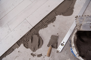 Image showing Ceramic wood effect tiles and tools for tiler on the floor