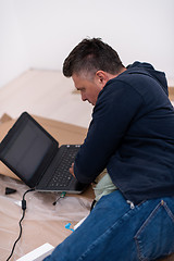 Image showing man using laptop while lying on cardboard box