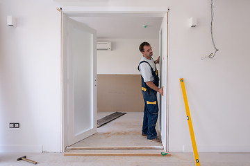 Image showing carpenters installing glass door with a wooden frame