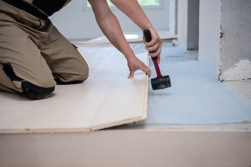 Image showing Professional Worker Installing New Laminated Wooden Floor