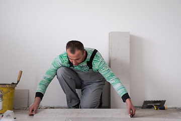 Image showing worker installing the ceramic wood effect tiles on the floor