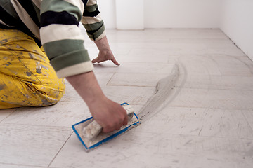 Image showing Tilers filling the space between ceramic wood effect tiles