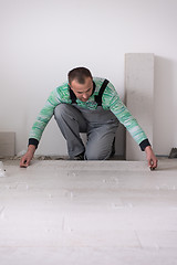 Image showing worker installing the ceramic wood effect tiles on the floor