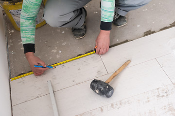 Image showing worker installing the ceramic wood effect tiles on the floor