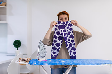 Image showing Red haired woman ironing clothes at home