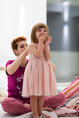 Image showing young mother helping daughter while putting on a dress