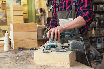 Image showing Worker grinds the wood box