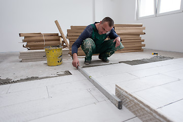 Image showing worker installing the ceramic wood effect tiles on the floor