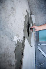 Image showing worker installing big ceramic tiles