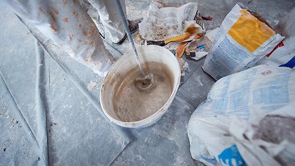 Image showing construction worker mixing plaster in bucket