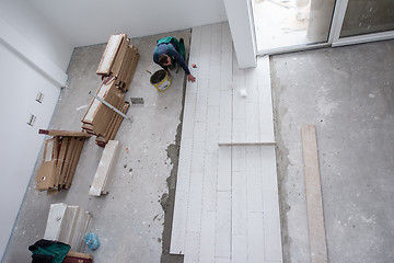 Image showing worker installing the ceramic wood effect tiles on the floor