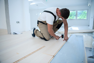 Image showing Professional Worker Installing New Laminated Wooden Floor