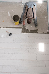 Image showing worker installing the ceramic wood effect tiles on the floor