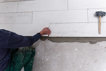 Image showing worker installing the ceramic wood effect tiles on the floor