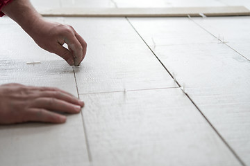 Image showing worker installing the ceramic wood effect tiles on the floor