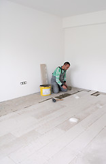 Image showing worker installing the ceramic wood effect tiles on the floor