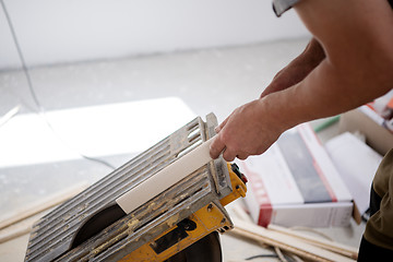 Image showing Man cutting laminate floor plank with electrical circular saw