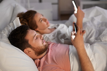 Image showing couple using smartphones in bed at night