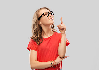 Image showing smiling student girl in glasses pointing finger up