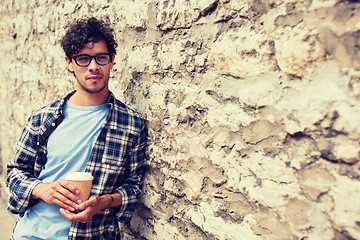 Image showing man in eyeglasses drinking coffee over street wall