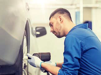 Image showing mechanic with screwdriver changing car tire