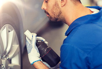 Image showing mechanic with screwdriver changing car tire