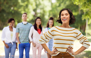 Image showing smiling woman with hands on hips over summer park