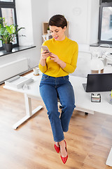 Image showing happy woman with smarthone sitting on office desk