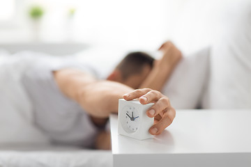 Image showing close up of man in bed reaching for alarm clock