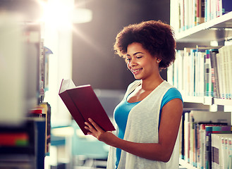 Image showing happy african student girl reading book at library