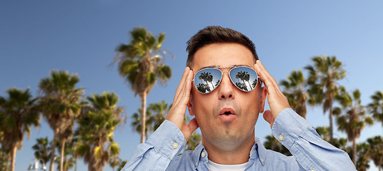 Image showing surprised man in sunglasses over palm trees