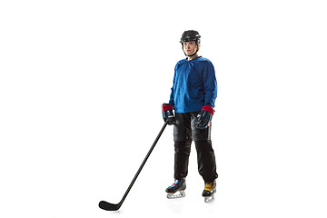 Image showing Young female hockey player with the stick on ice court and white background