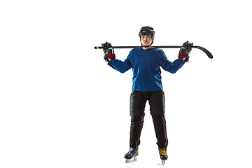 Image showing Young female hockey player with the stick on ice court and white background