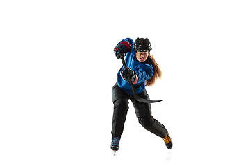 Image showing Young female hockey player with the stick on ice court and white background