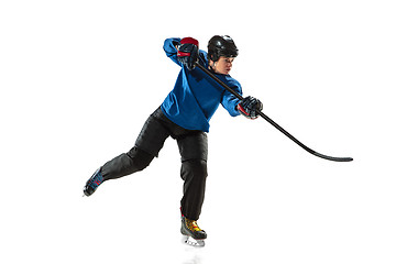 Image showing Young female hockey player with the stick on ice court and white background